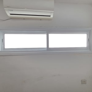 חלון אלומיניום עם מזגן על קיר לבן