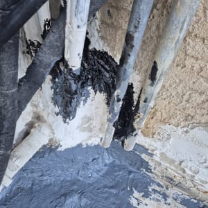 צינורות עם חומר איטום שחור ואפור על קיר