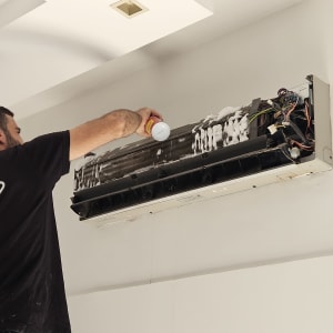 אדם מנקה מזגן עם תרסיס קצף