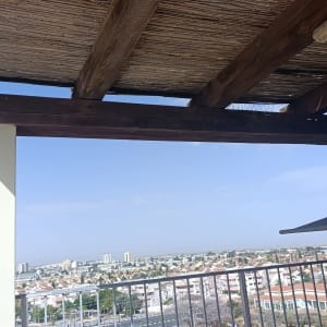 מרפסת עם גג עץ ונוף עירוני ברקע