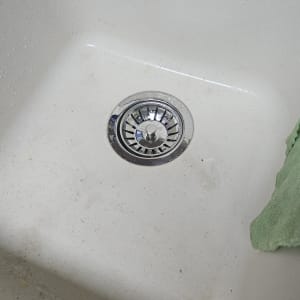 כיור עם ניקוז מתכת ומטלית ירוקה בצד