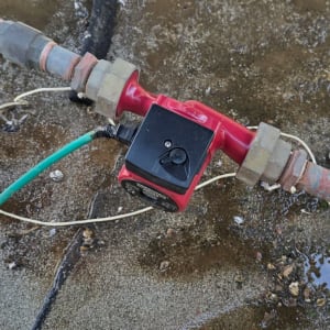 צינור עם שסתום אדום ומחברים על קרקע רטובה