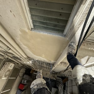 עובד בגובה עם מגני ברכיים על קיר חיצוני