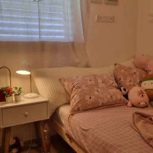 חדר שינה עם מיטה, כריות, מנורה ושולחן קטן