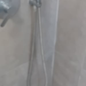 ראש מקלחת וכפתור שליטה על קיר אריחים