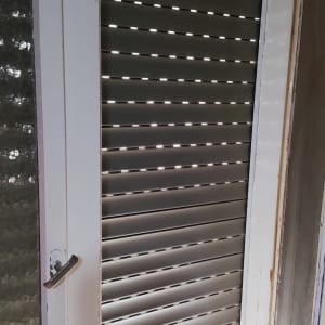 תריסים סגורים עם חריצים לאור על דלת זכוכית