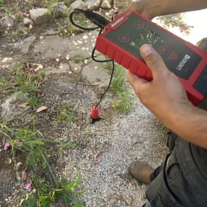 אדם מחזיק מכשיר לגילוי נזילות בגינה