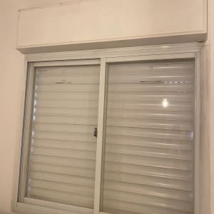 חלון עם תריסים סגורים על קיר לבן