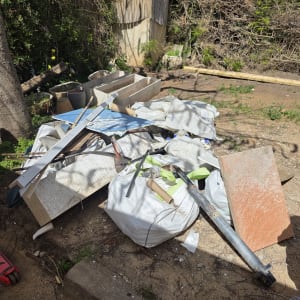 ערימת פסולת בנייה בחצר עם צינורות ולוחות עץ