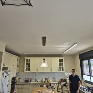 חשמלאי עובד במטבח עם סולם וכלי עבודה