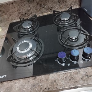 כיריים גז עם ארבעה מבערים על משטח שיש.