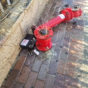 ברז כיבוי אש שבור עם מים זורמים על המדרכה