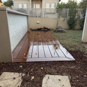 דק עץ בגינה עם שביל אבנים ואדמה