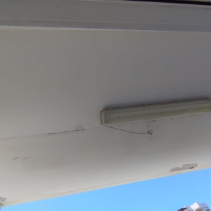 תאורת פלורסנט תלויה על תקרה עם חוטים חשופים