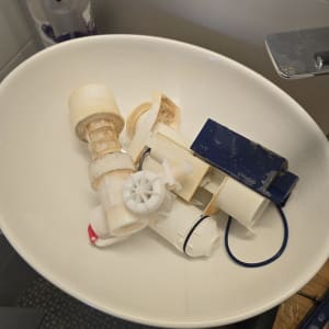 חלקי מנגנון ניאגרה סמויה שפורקו והונחו בכיור במהלך תיקון