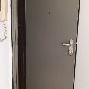 דלת אפורה עם ידית מתכת פתוחה חלקית