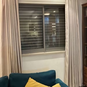 וילונות בהירים ליד חלון עם ספה וכריות צהובות