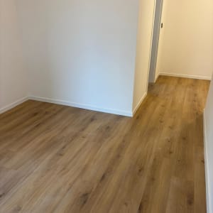 רצפת פרקט עץ בחדר ריק עם קירות לבנים