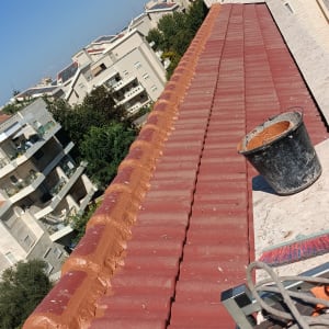 גג רעפים אדום עם דלי וכלים על הגג