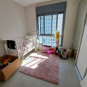 חדר ילדים עם מיטת תינוק, צעצועים ושטיח ורוד