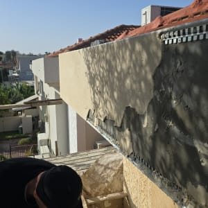 עבודת טיח על קיר חיצוני עם אדם בעבודה