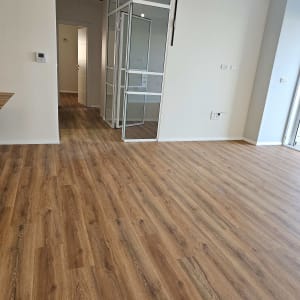 רצפה נקייה מעץ בחדר ריק עם דלת זכוכית