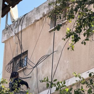 אדם עובד על חוטי חשמל על קיר חיצוני