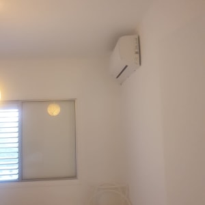 קיר צבוע בלבן עם מזגן וכיסא לבן