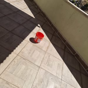 דלי אדום על רצפת מרפסת מרוצפת