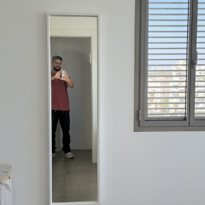 מראה מלבנית גדולה בעלת מסגרת לבנה התלויה על הקיר