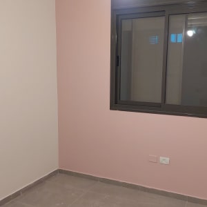 חדר צבוע בצבע ורוד עם חלון ונורה תלויה