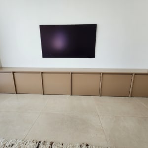 ארון עץ חום מתחת לטלוויזיה על קיר לבן