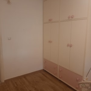 קירות צבועים בלבן בחדר ילדים מרוהט עם ארון בגדים