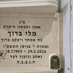 מצבה עם כיתוב בעברית ופרחים חקוקים