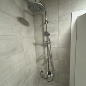 ראש מקלחת מותקן על קיר אריחים בחדר אמבטיה