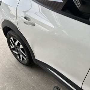 מכונית לבנה עם שריטות קלות על הדלת האחורית