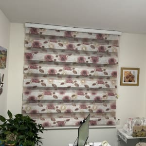 חדר עם וילונות פרחוניים, צמחים ותמונות על הקיר