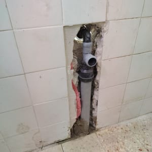 צינור מים מותקן בקיר עם אריחים שבורים