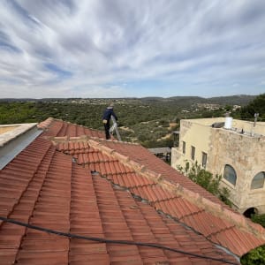 גג רעפים אדום עם אדם עובד על תיקון