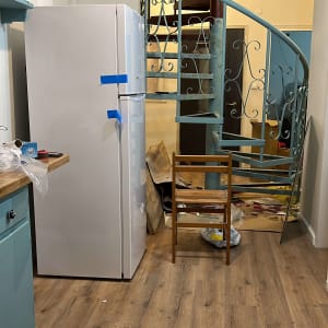 מקרר עם סרטי הדבקה, מדרגות לולייניות, כלים על הרצפה