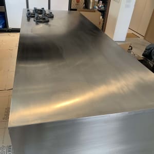 משטח מתכת גדול עם חלקים מונחים עליו בחדר עבודה.