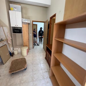 חדר עם מדפים ריקים, אנשים עומדים בפתח הדלת