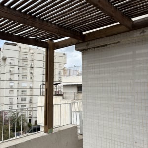 פרגולה מעץ על מרפסת עם בניינים ברקע