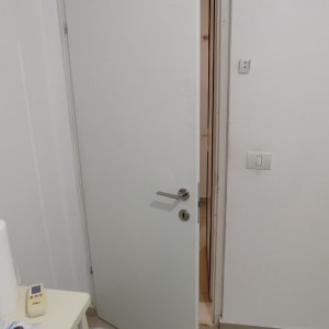 דלת פנים לבנה מעוצבת פתוחה למחצה בפתח חדר ממ"ד