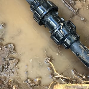 צינור שחור עם מחבר במים ובוץ