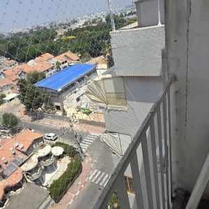 מרפסת עם רשת נגד יונים ונוף עירוני
