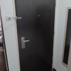 דלת חומה עם ידית מתכת וקיר לבן