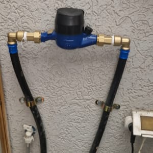 מד מים כחול עם צינורות מחוברים לקיר