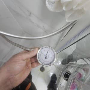 מד לחץ מים במקלחת, יד מחזיקה את המכשיר