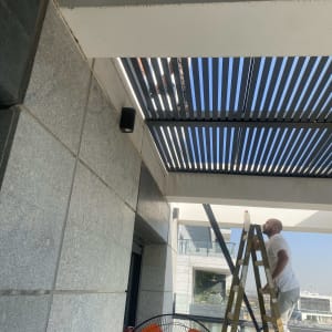 אדם על סולם מתקין פרגולת אלומיניום